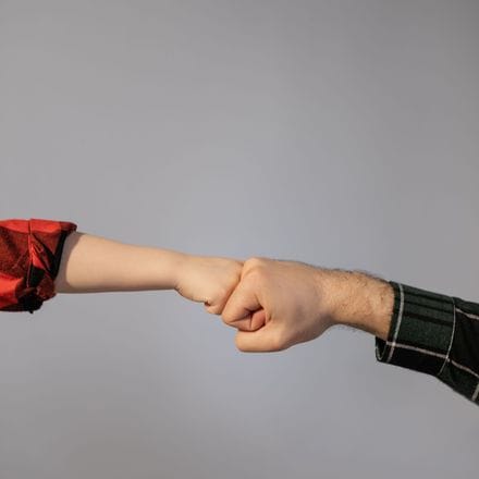 A child's fist bumping a grown-up's fist