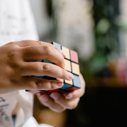 A child's hands turning a scrambled Rubik's cube