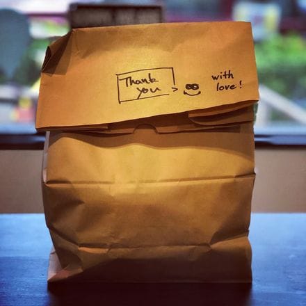 A paper lunch bag with "thank you, with love" written on it